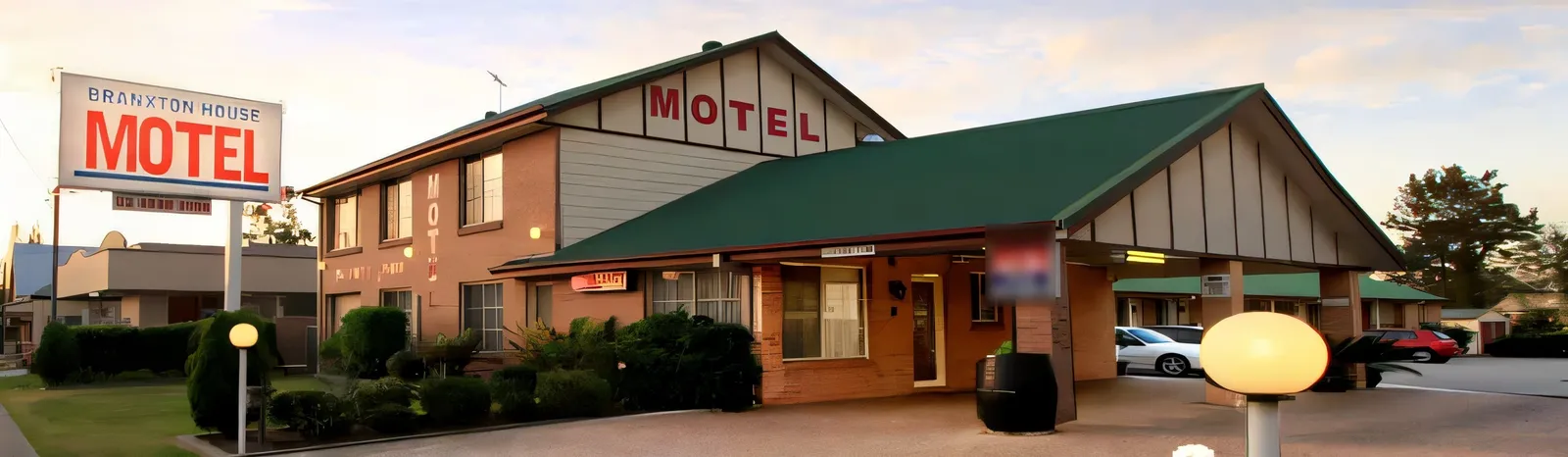 Branxton House Motel at dusk: the brick motel with its green roofs and roadside sign on the New England Highway